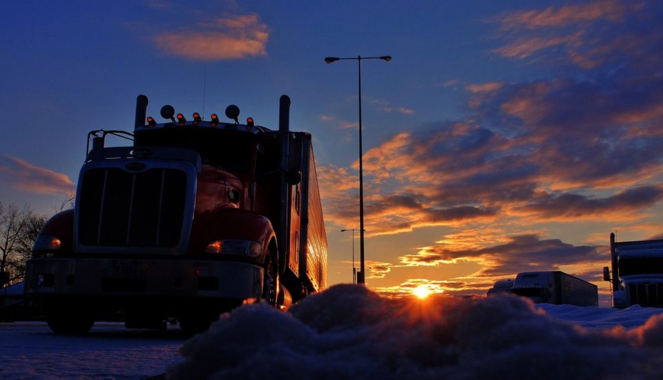 Shipping truck driving at sunrise