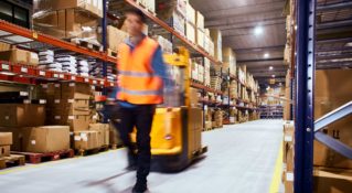 A warehouse employee walks moves inventory for direct to consumer shipping