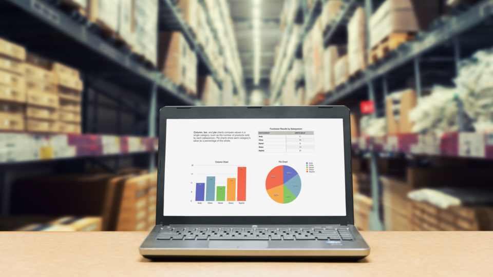 A laptop in a warehouse with supply chain analytics and graphs on the screen. Visibility into their supply chain can help companies get the best freight shipping options