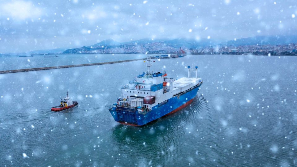 An international shipping vessel on the ocean while it's snowing