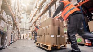 Workers push goods in a warehouse as part of warehouse distribution services