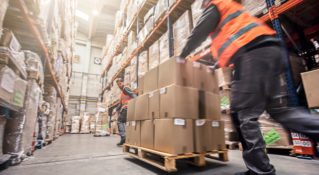 Workers push goods in a warehouse as part of warehouse distribution services