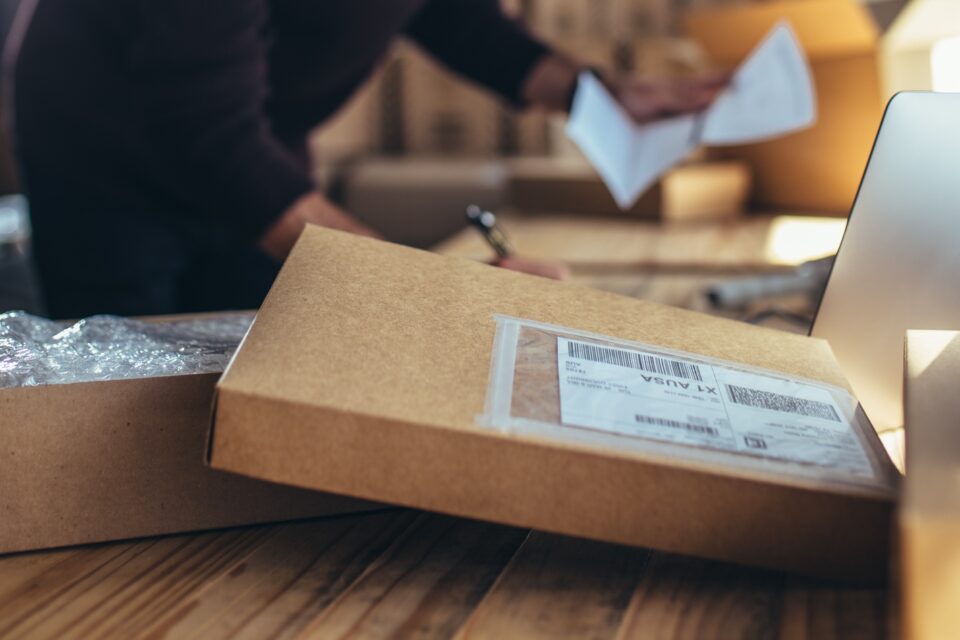 Close-up shot of a parcel with a person in the background checking a receipt